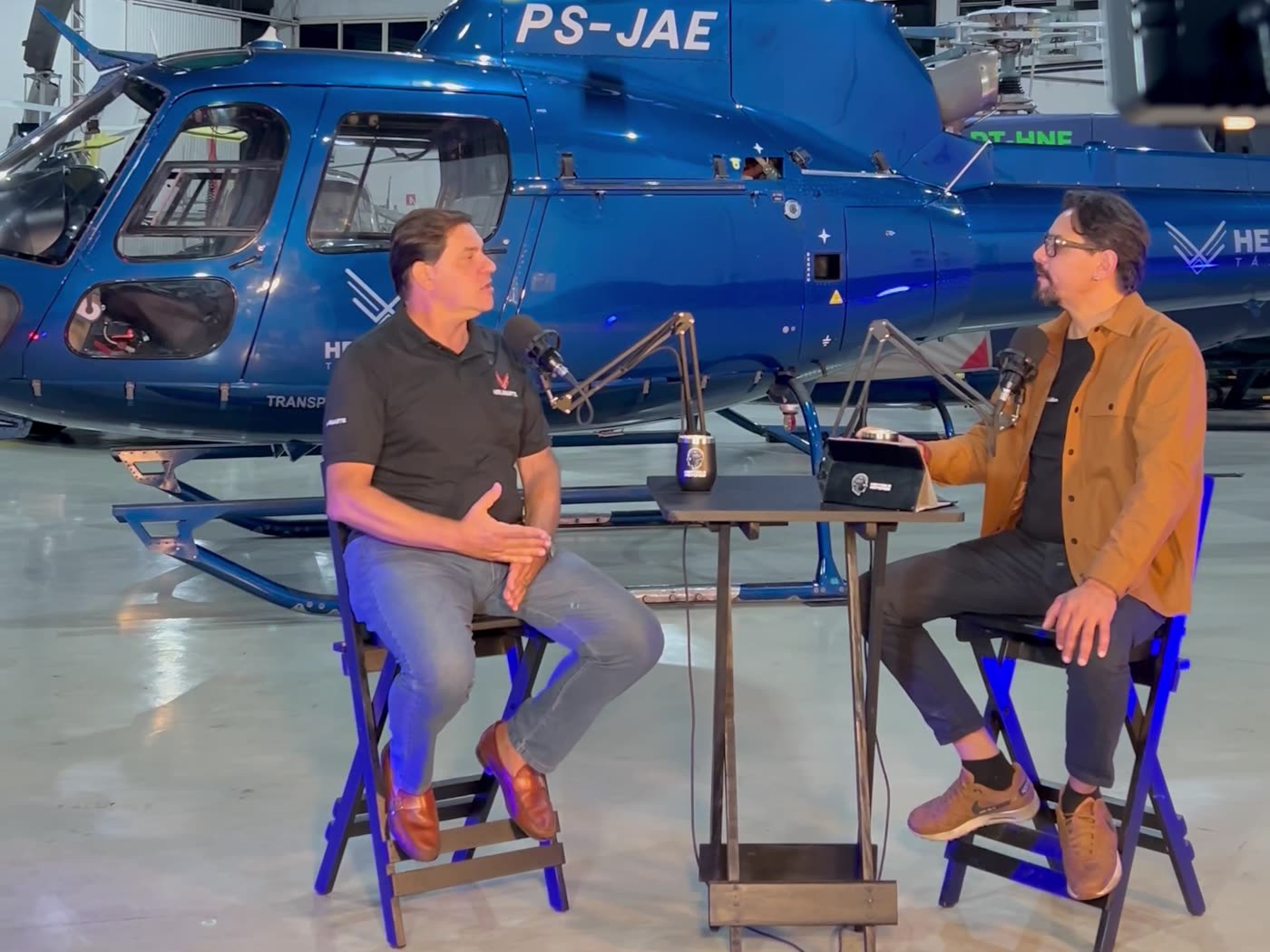 Entrevista gravada em um hangar, ao lado de um helicóptero